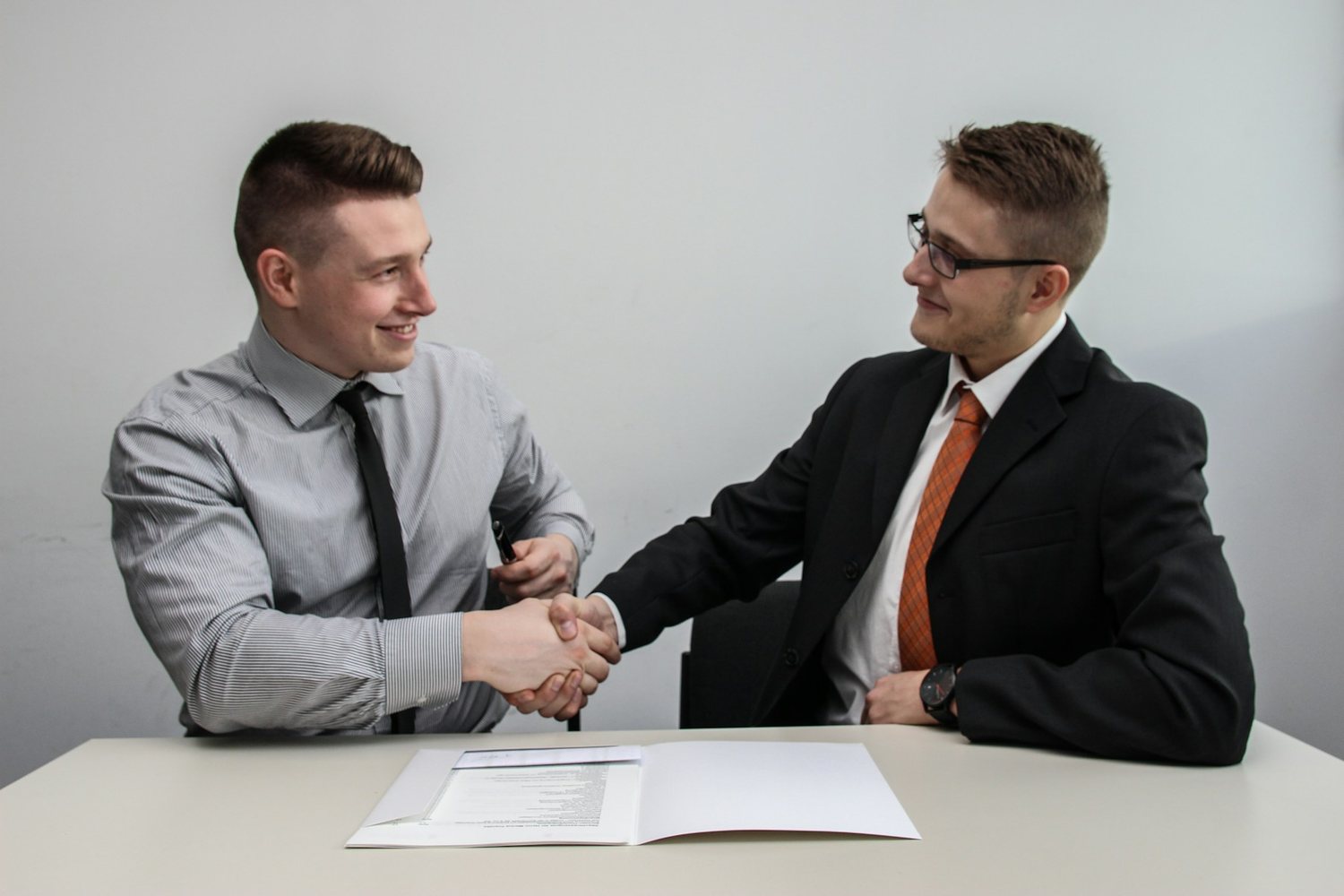 Two men shaking hands over membership paperwork